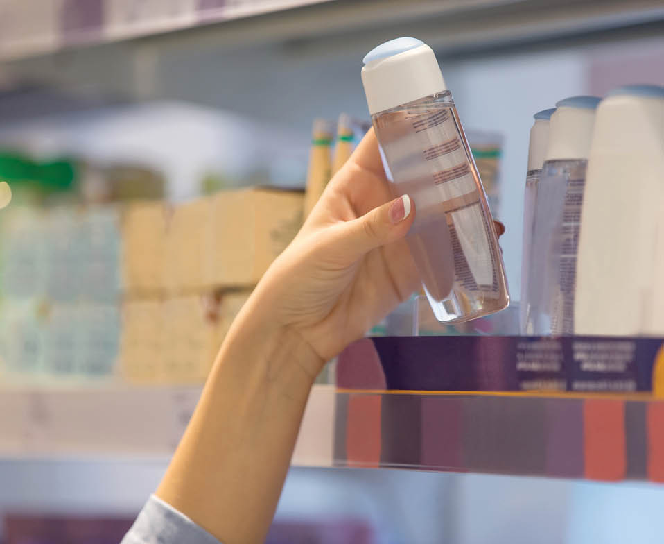 Woman reaching for hygiene products in supermarket, looking for product on shelf