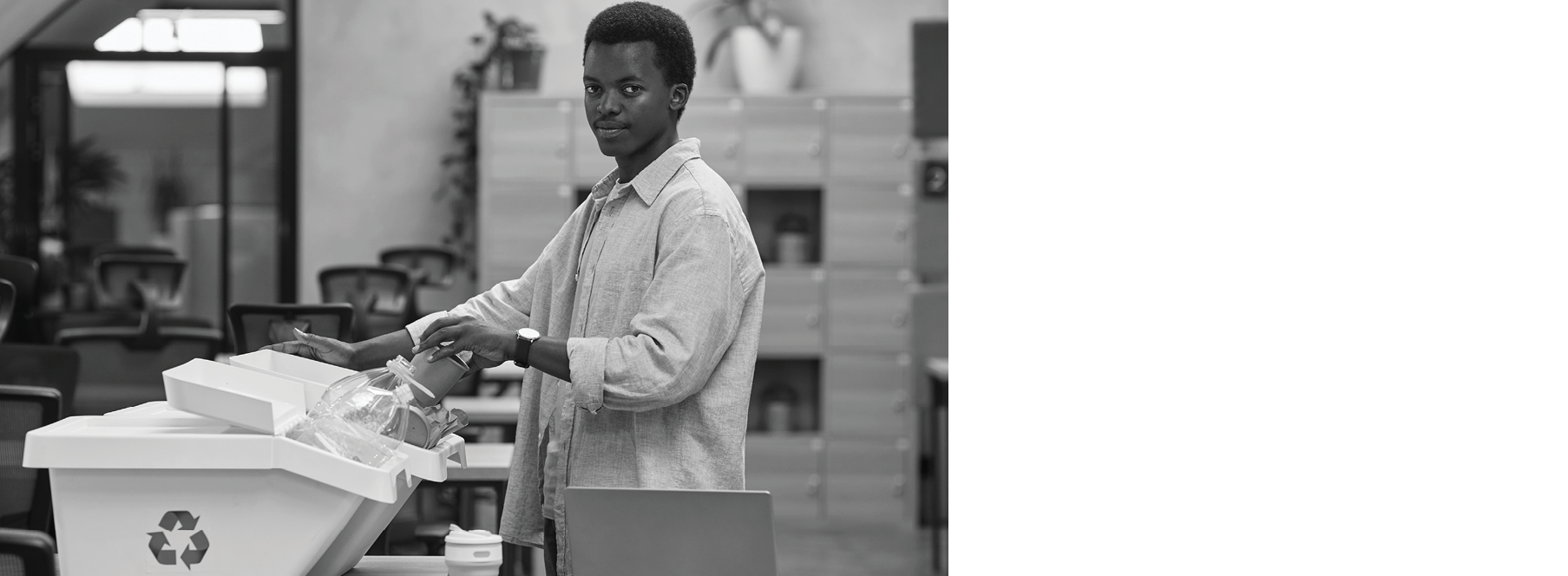 Side view portrait of young African-American man putting paper cup into waste sorting bin in office, copy space
